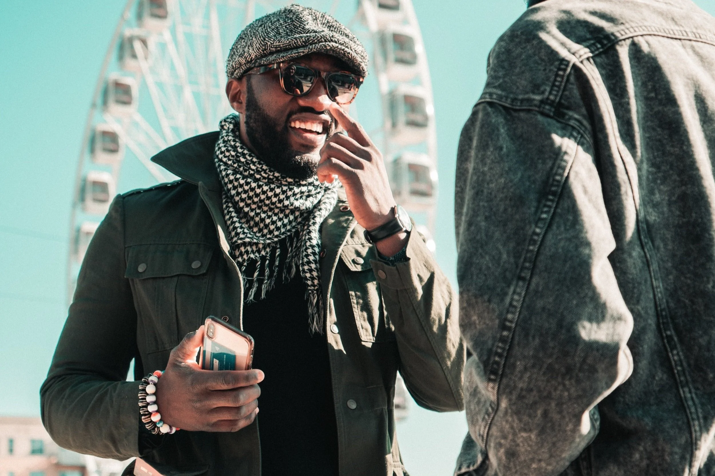 Stylish man smiling at his friend with a ferris wheel in the background