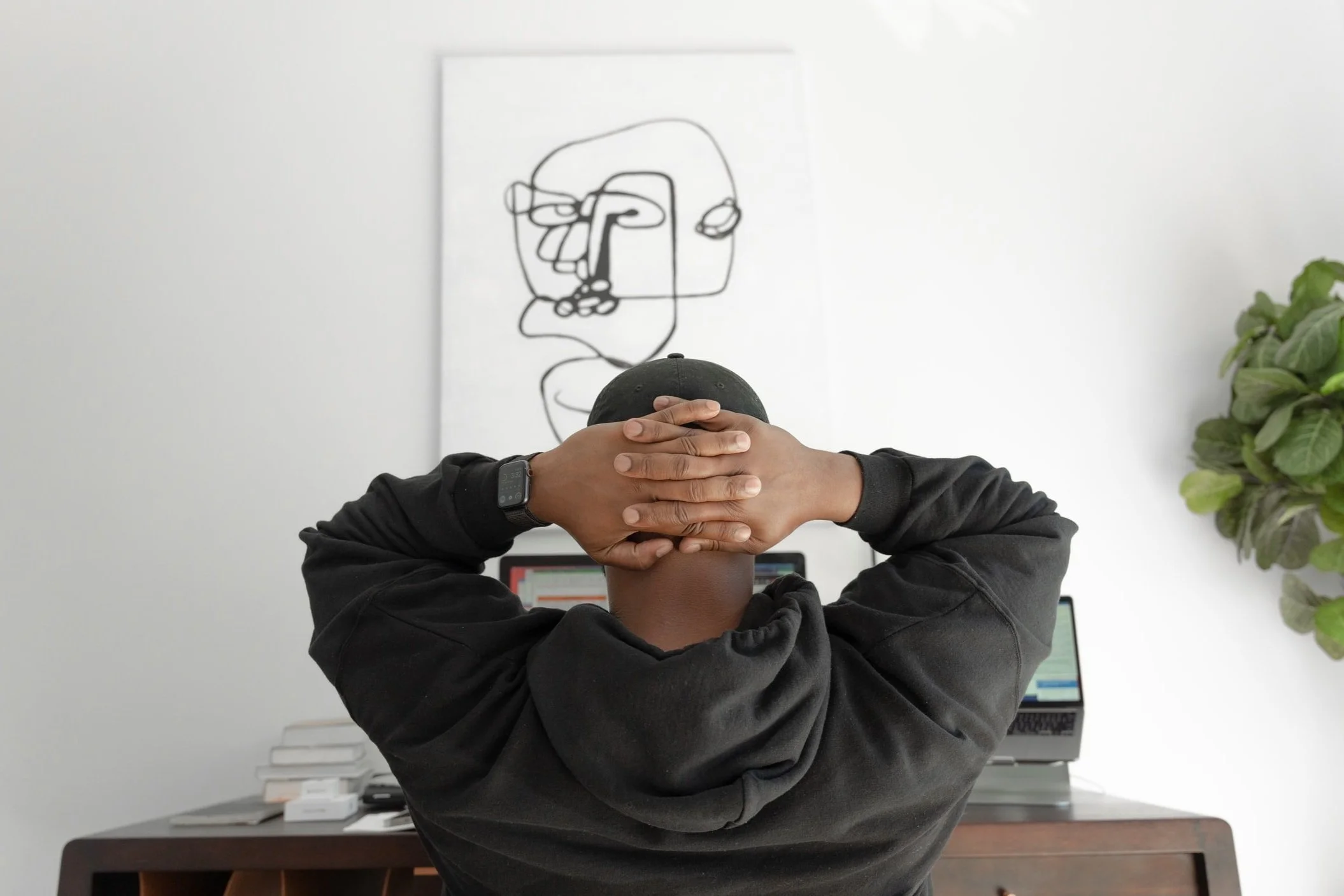 Man sitting with his hands clasped behind his head, looking at an abstract portrait