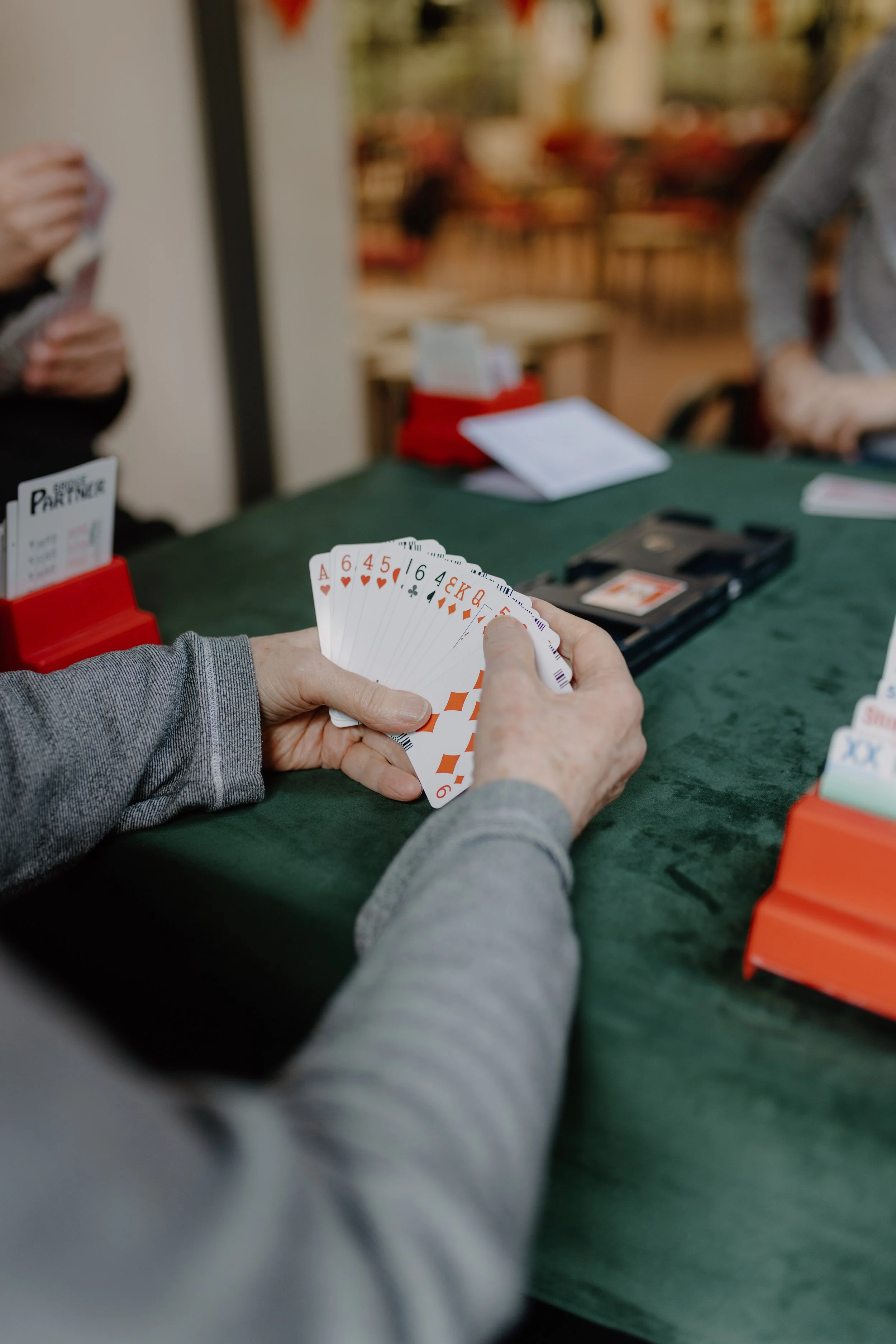 A person holding a hand of playing cards that includes an Ace of hearts, 6 of hearts, 4 of hearts, 5 of hearts, 6 of clubs, 4 of diamonds, 3 of hearts, and 5 of diamonds, at a poker game in a casino or poker room.