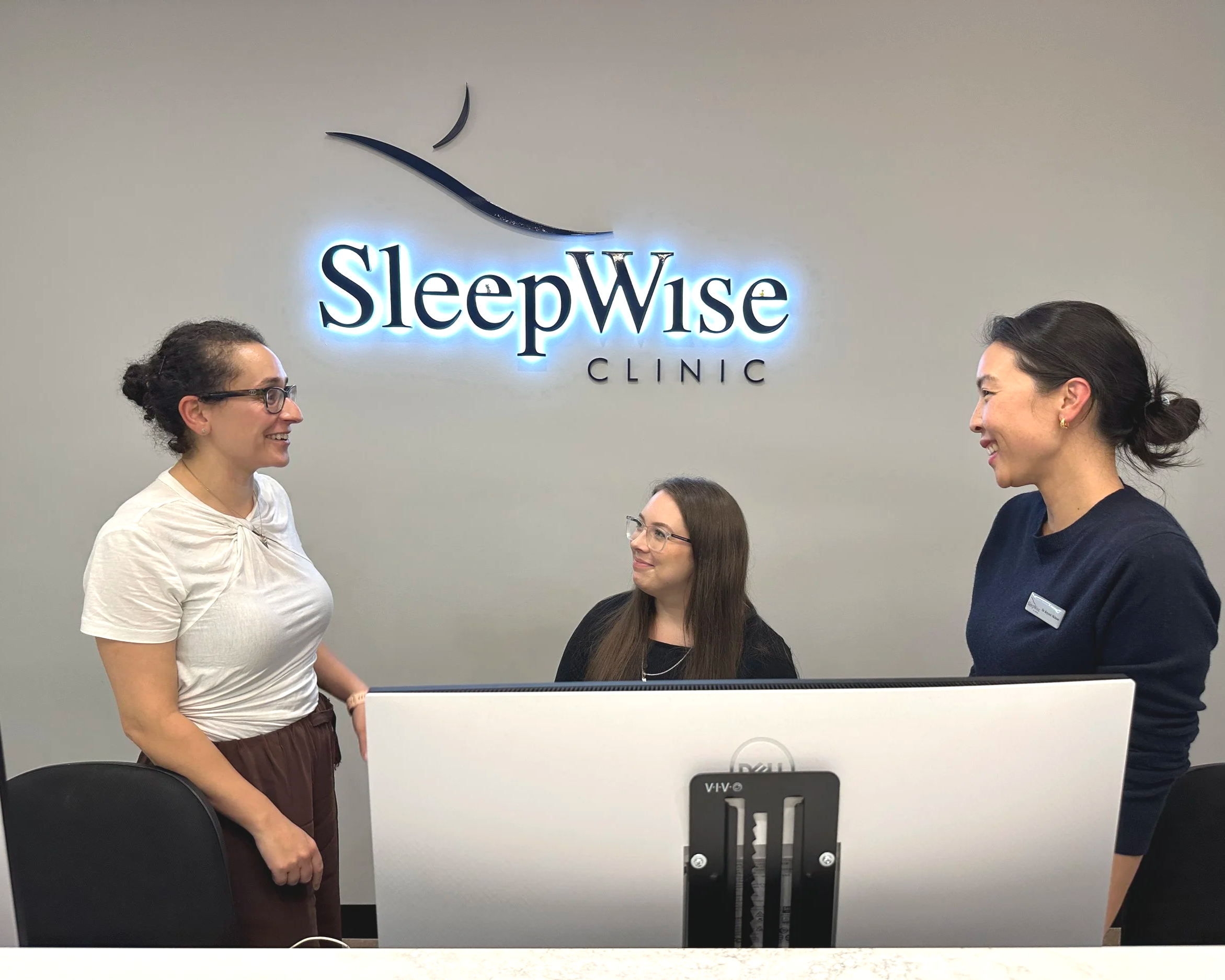 reception staff and sleep medicine dentists at the front desk welcoming patients