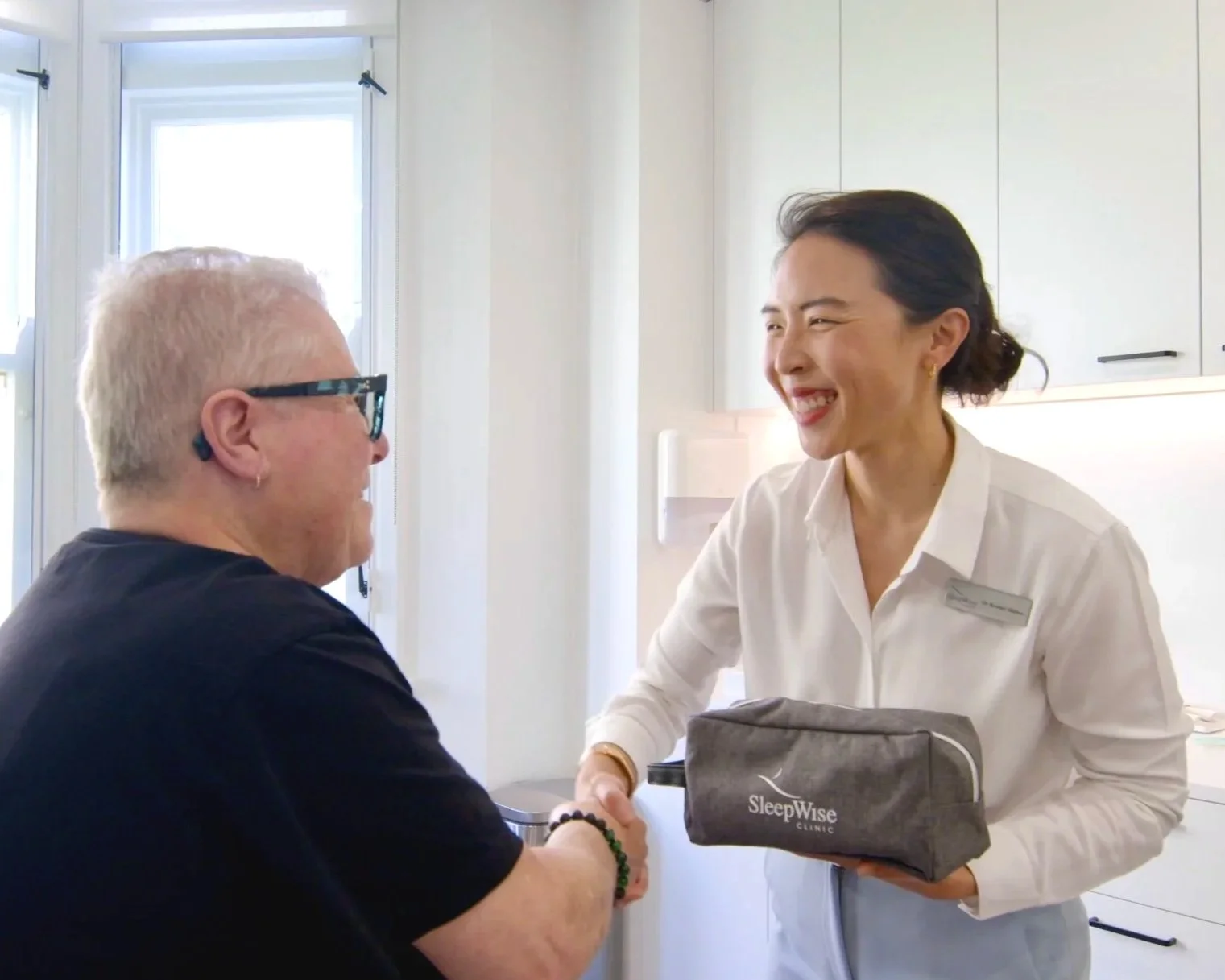Smiling patient and sleep medicine dentist shaking hands upon a successful fitting of a mandibular advancement splint to treat severe sleep apnoea