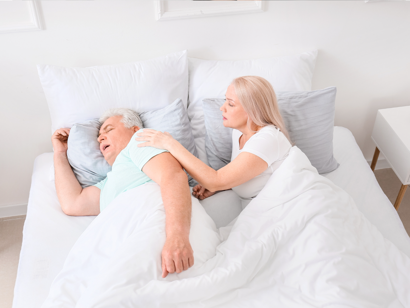 concerned wife waking snoring man from sleep