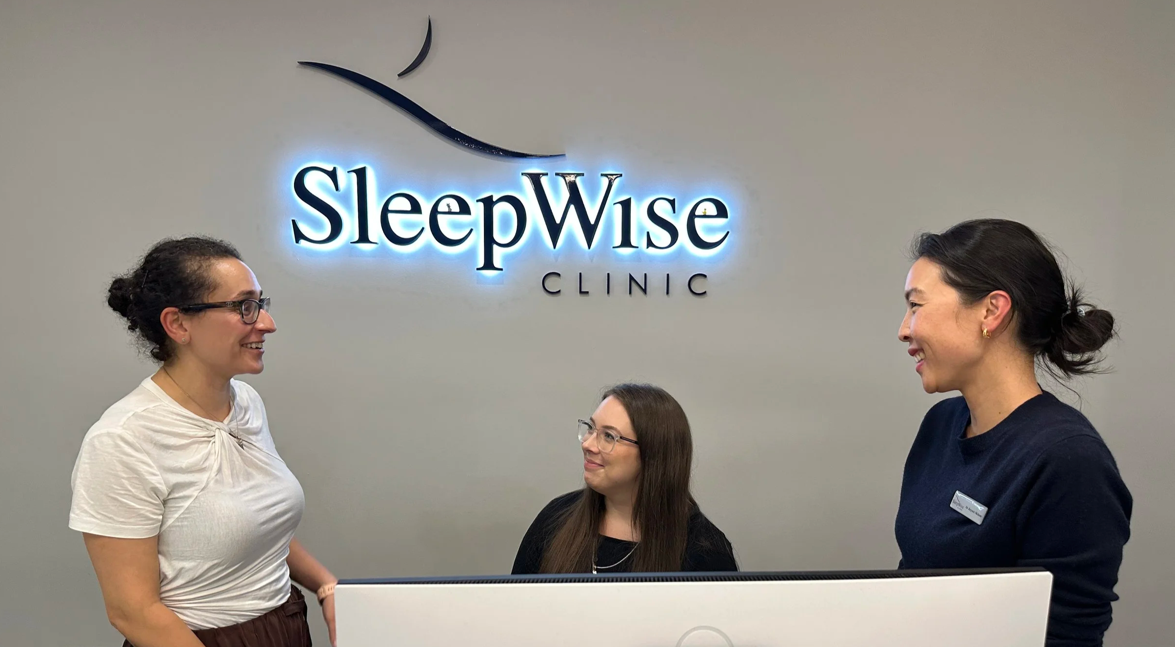sleep medicine dentists who can help you with CPAP treatment alternatives and a smiling front desk staff member gathered around to discuss a patient