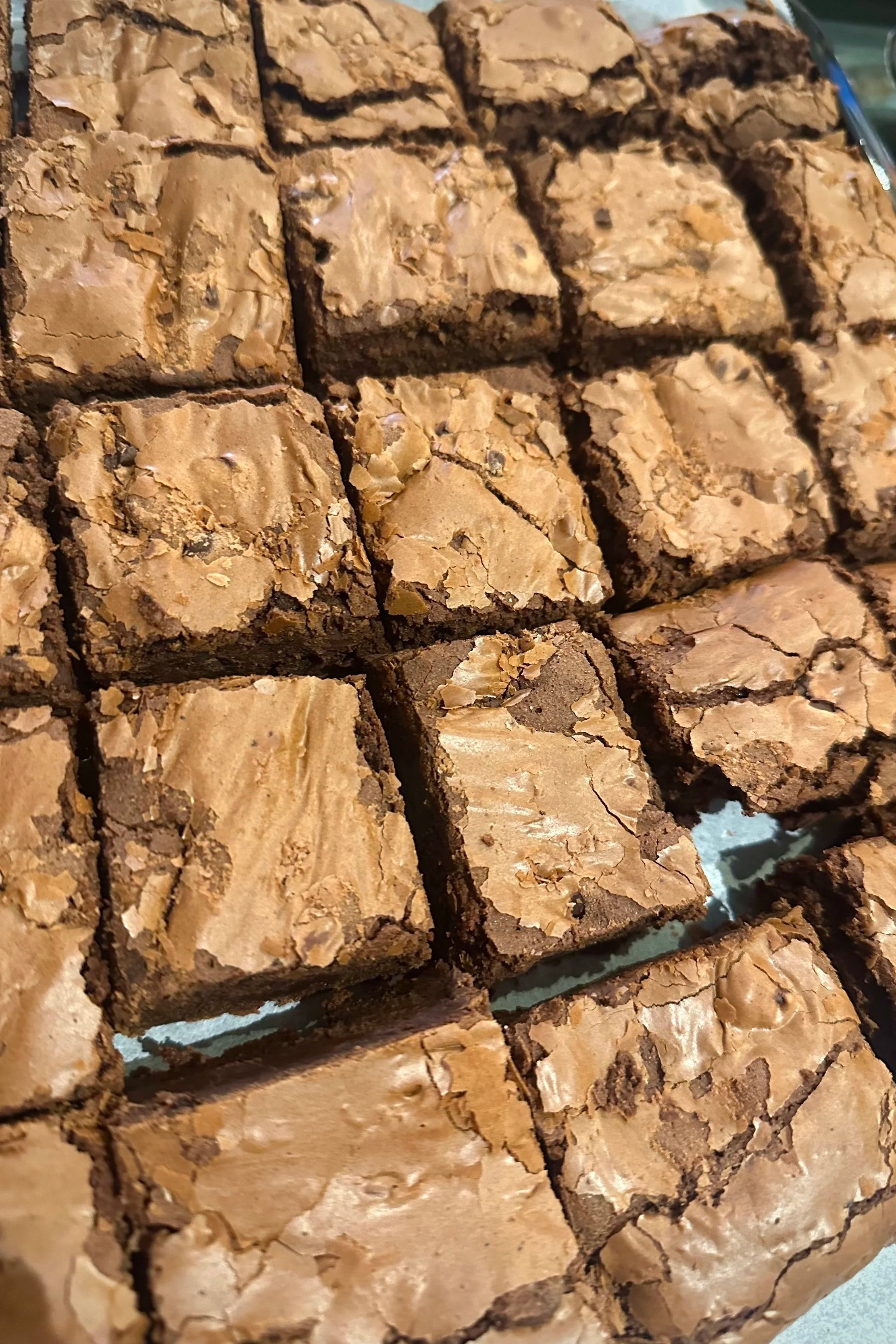 Close-up of chocolate brownies with cracked tops in a baking tray.