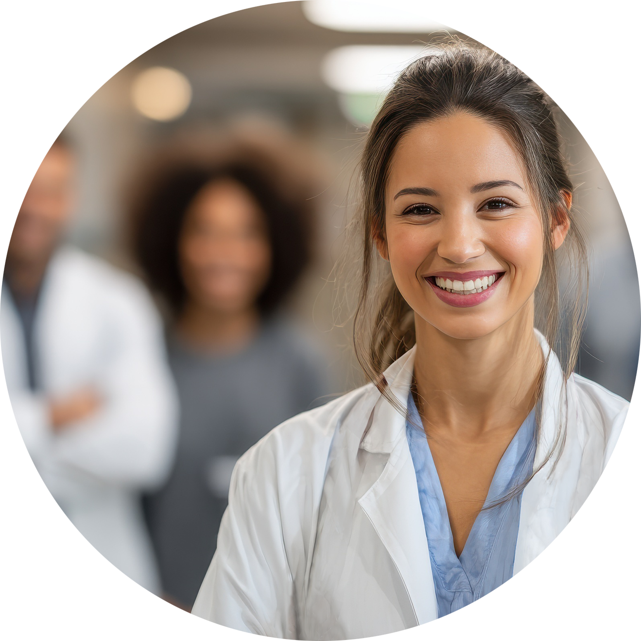 A smiling young woman in medical scrubs with a group of blurred colleagues in the background.