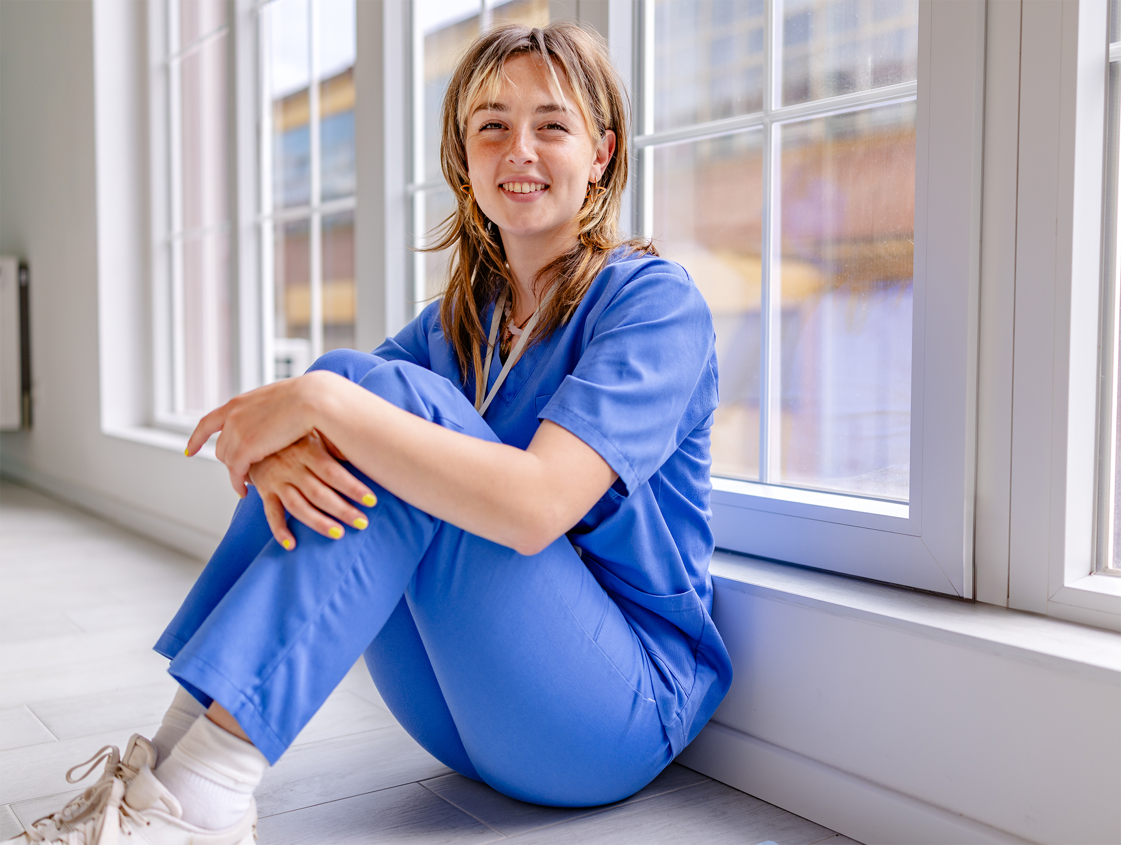 Kvinne som sitter på gulvet og smiler