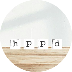 Four Scrabble tiles spelling 'h p p d' on a wooden surface.