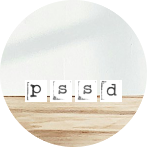 Four small white cards with black lowercase letters spelling 'p', 's', 's', 'd' on a wooden surface against a white background.
