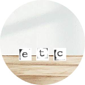 Three small blocks with letters spelling "etc" on a wooden surface against a white background.