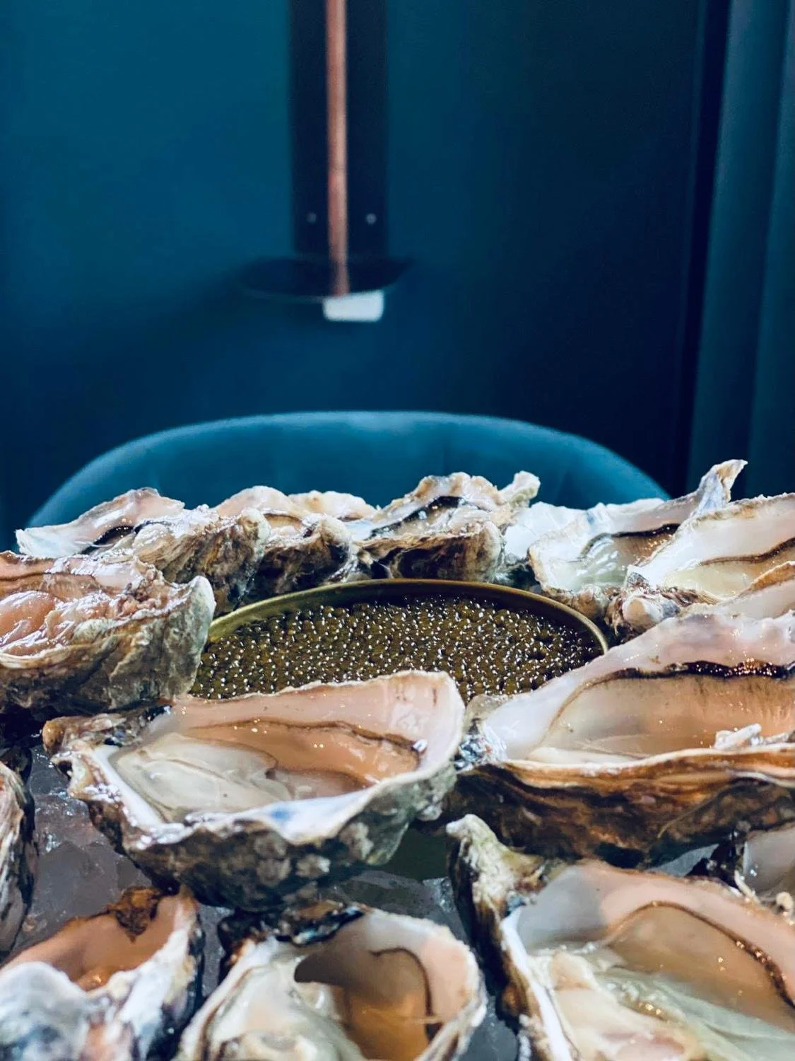 Several open oyster shells with a bowl of oyster pearls in the center, on a table.