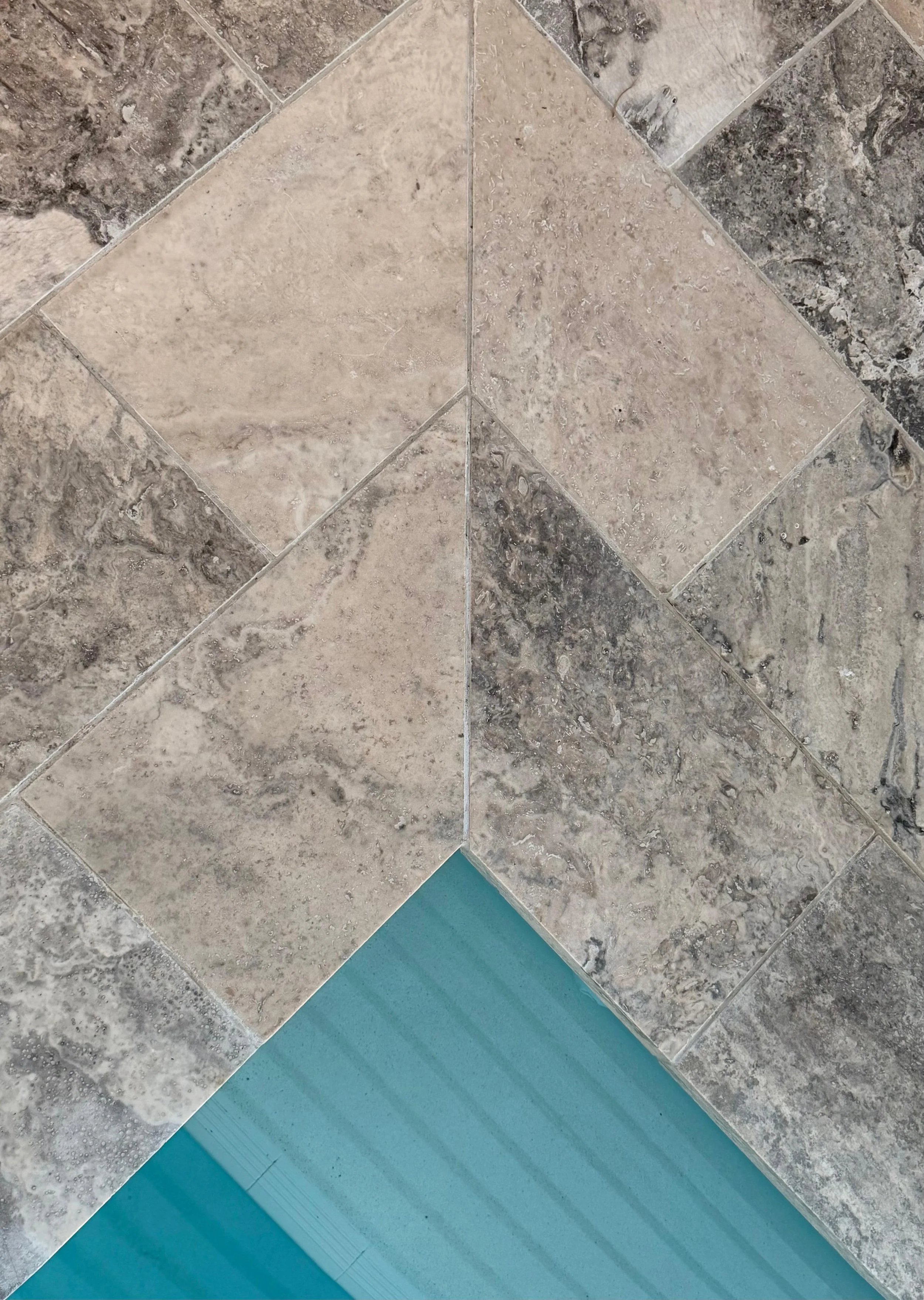 Close-up image of silver travertine paved floor including shades of beige, grey, and blue.