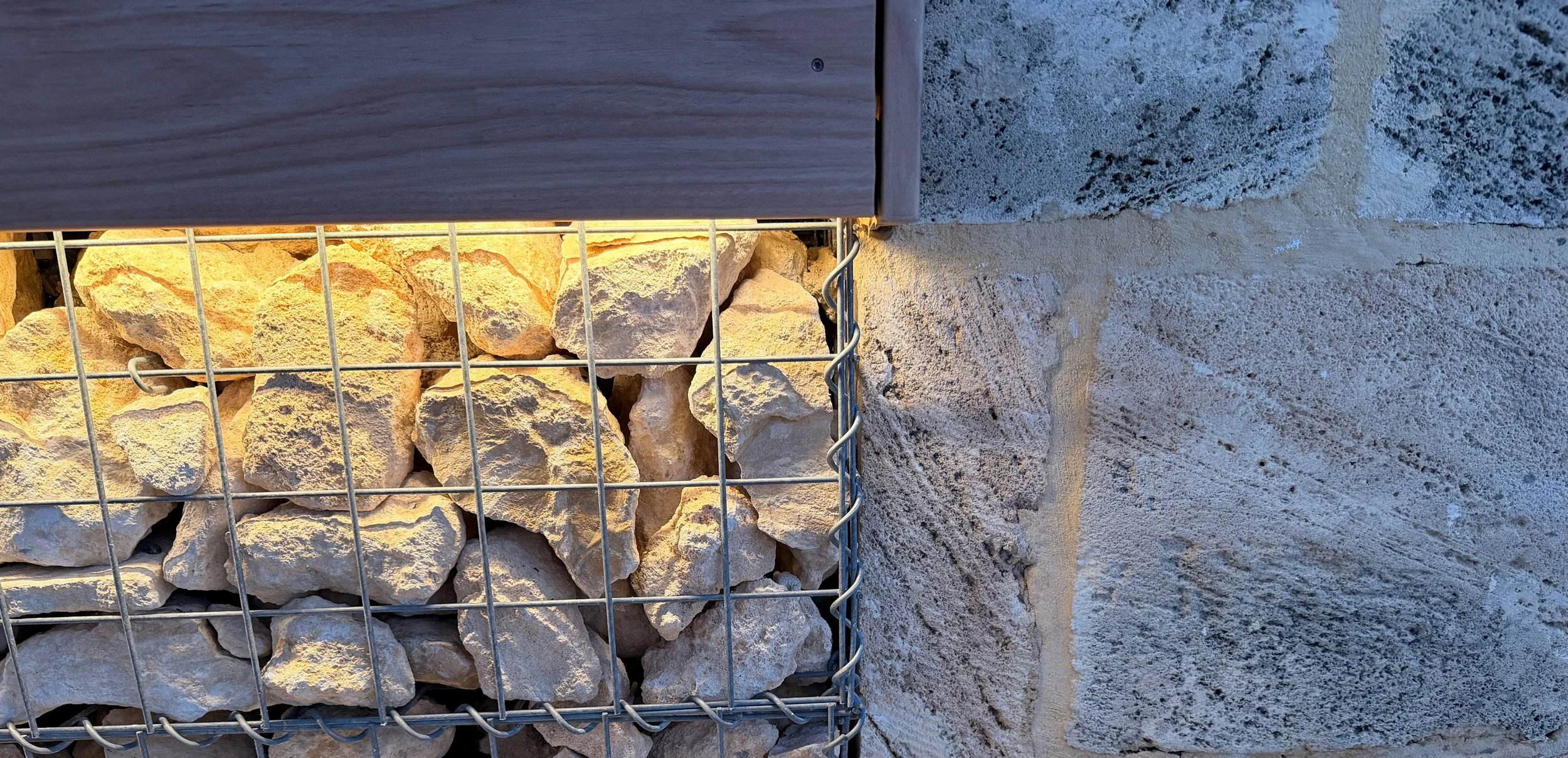 gabion wall lit up by LED strip tied in to natural limestone wall