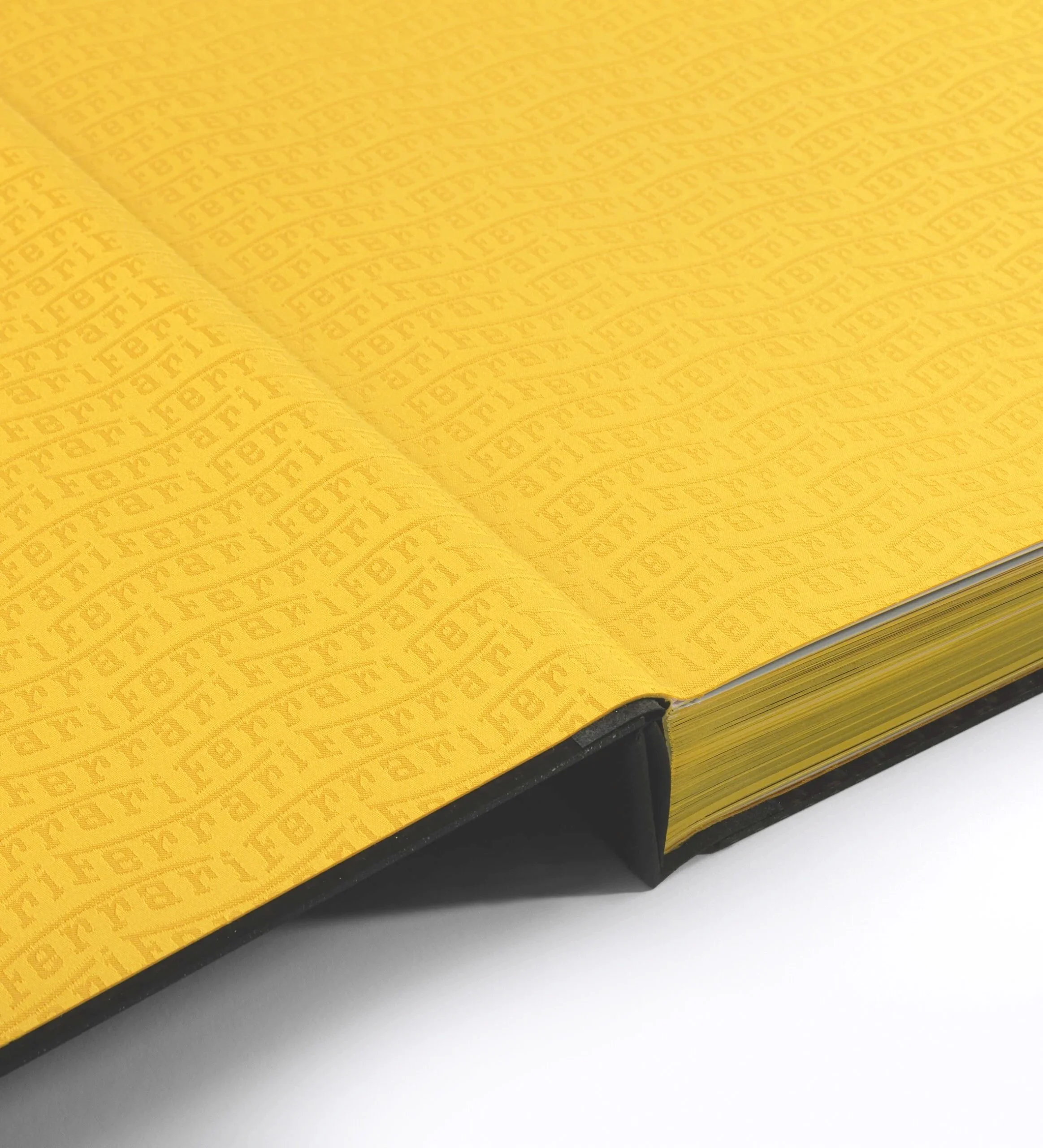 Dettaglio di un libro con copertina gialla a motivi ripetuti con scritte o simboli, e pagine dorate.