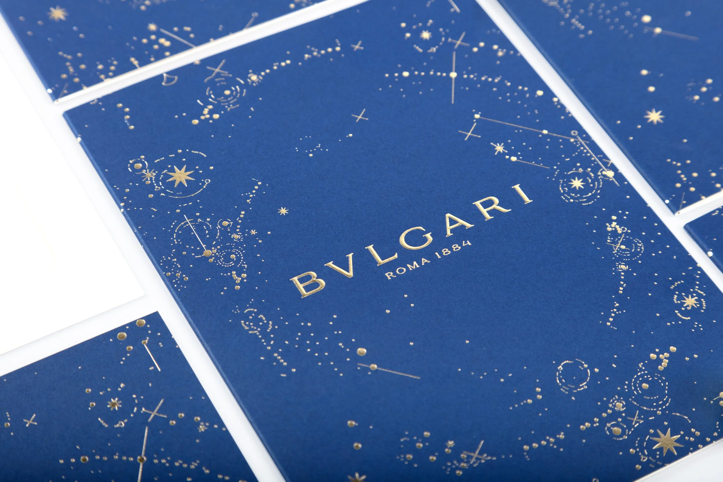 Scatole blu con dettagli dorati e il logo Bvlgari, con scritta ROMA 1884, decorazioni di stelle e costellazioni dorate.
