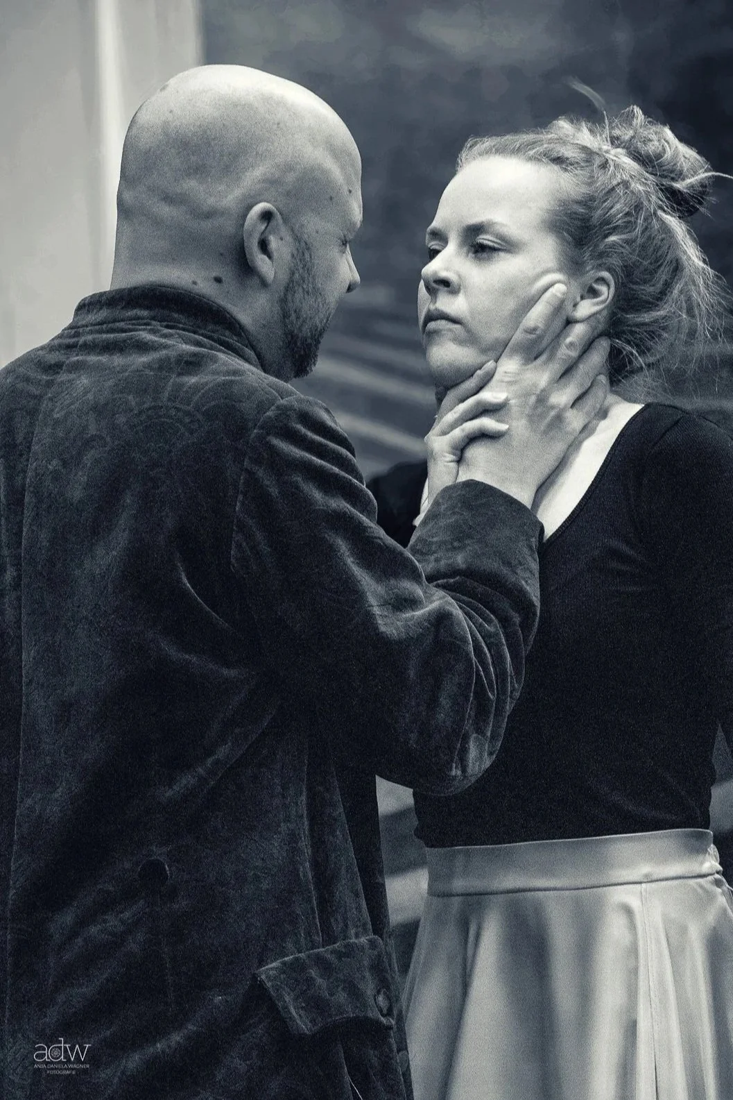 A man with a shaved head and beard gently holds a woman's face, who has her eyes closed and appears emotional. The scene is intense and intimate.
