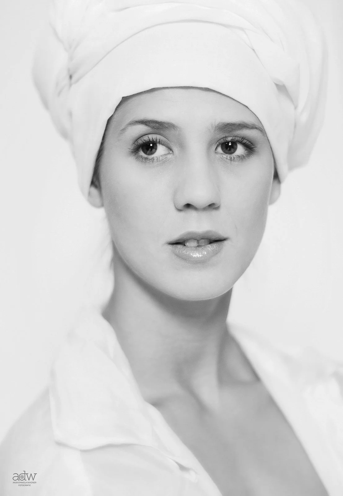 Black and white portrait of a woman wearing a headscarf, with flowing hair, gazing slightly to the side.