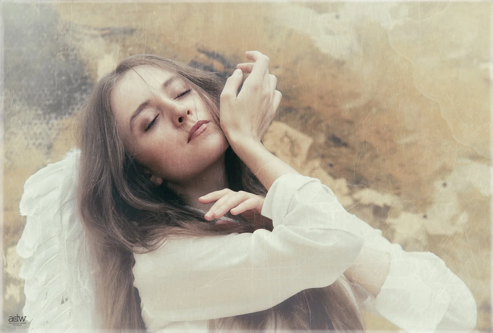 A woman with long brown hair, wearing a white dress, is sitting with her eyes closed and a peaceful expression on her face, surrounded by a natural, earthy background.