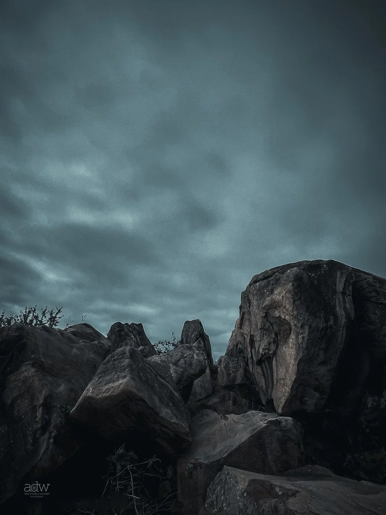 Dark, cloudy sky over large scattered rocks and boulders in a natural outdoor setting.