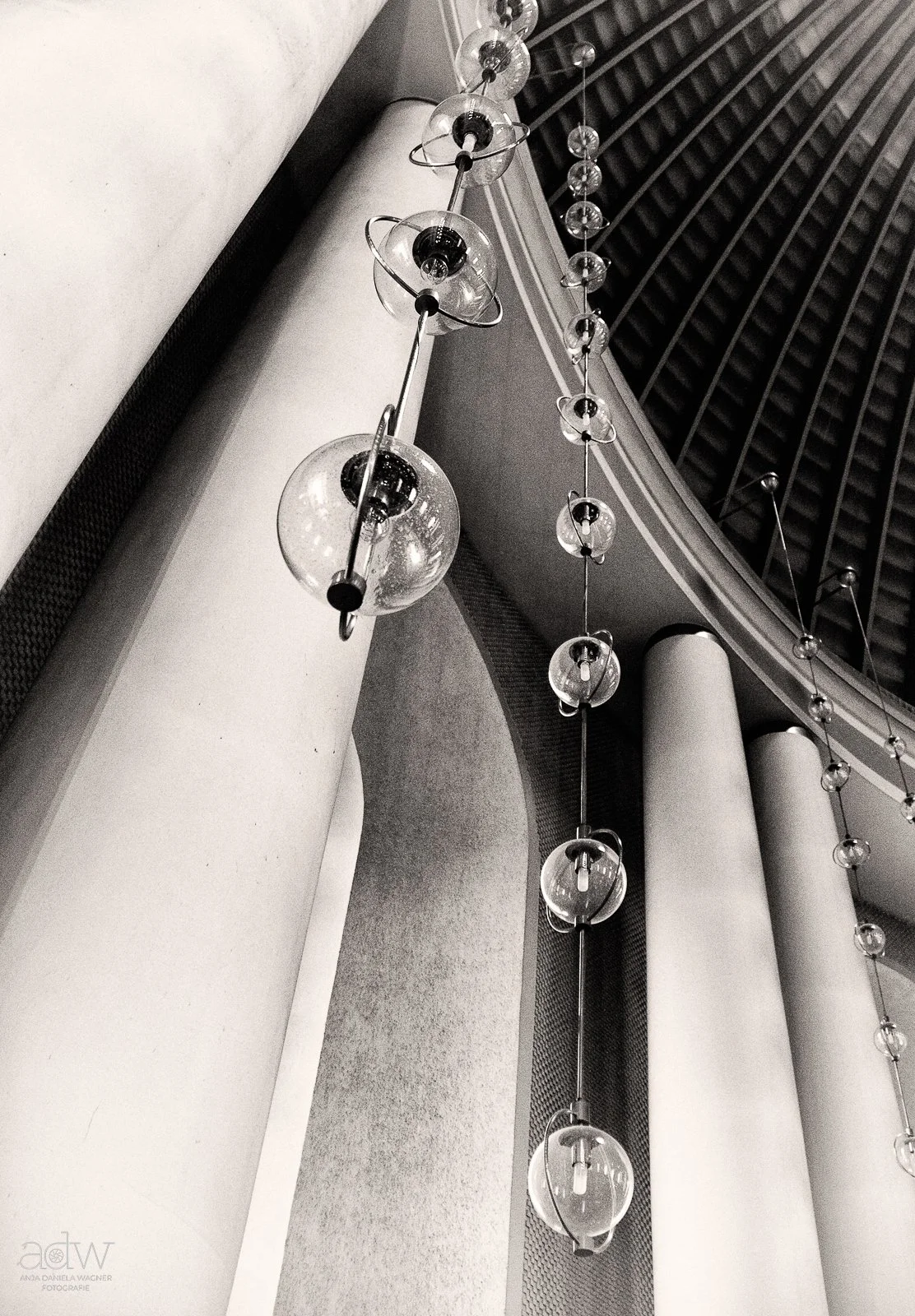A modern chandelier with spherical glass fixtures hanging from the ceiling in a building interior.
