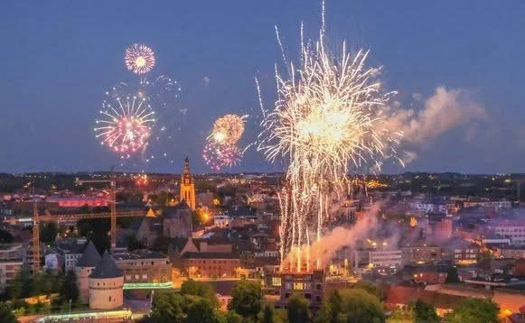Vuurwerk dat afgaat boven een stad tijdens de nacht, met veel kleurrijke explosies in de lucht.