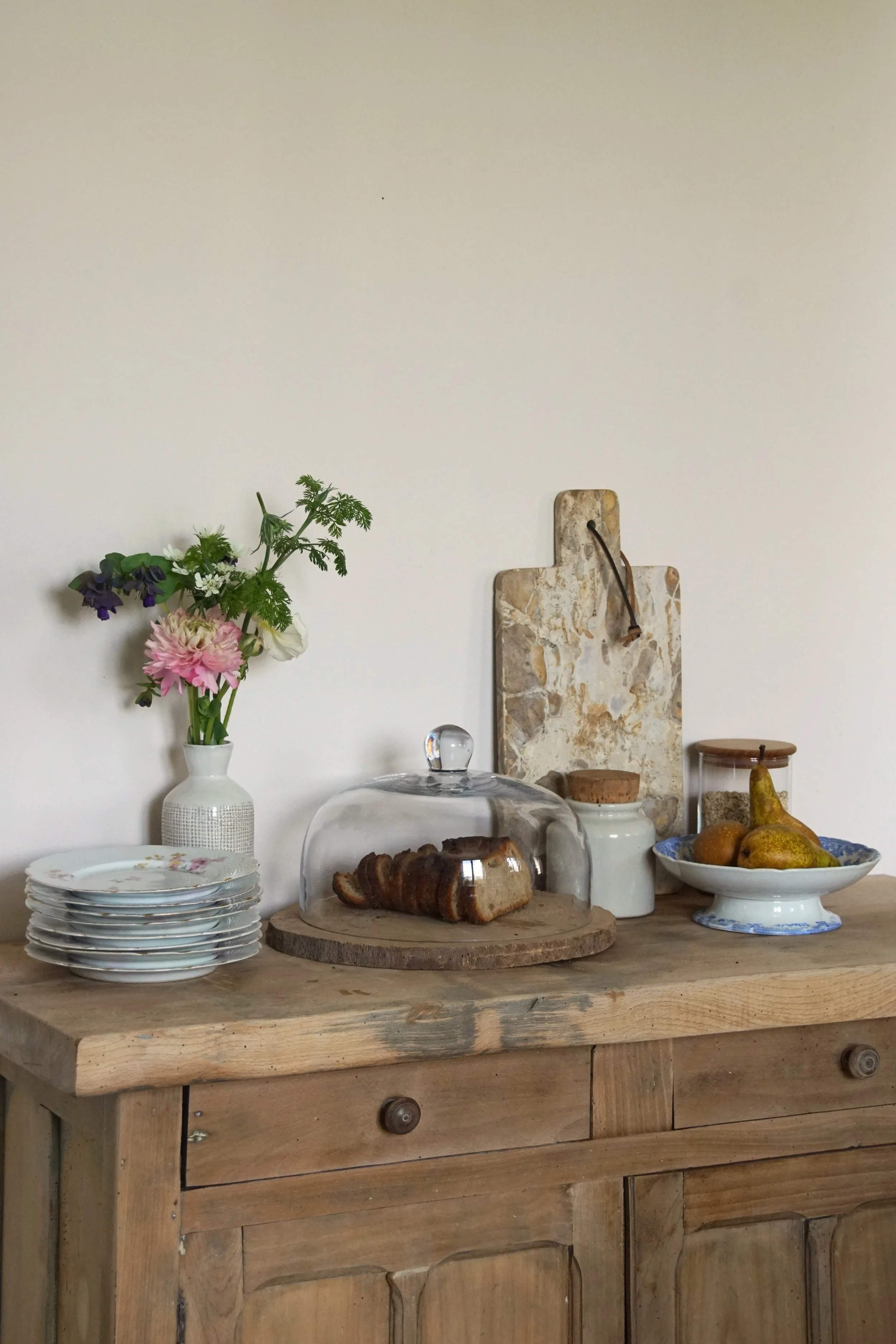 Stylisme d'intérieur d'un meuble en bois avec de la vaisselle, des éléments d'art de vivre, un vase avec des fleurs et de la décoration d'intérieure.