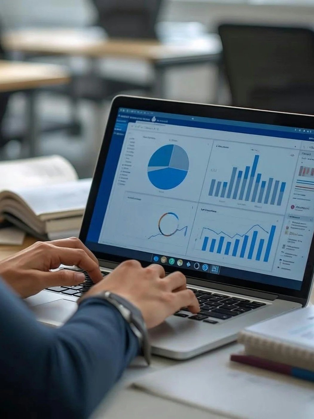Person working on a laptop with data analytics and charts on the screen in an office setting.