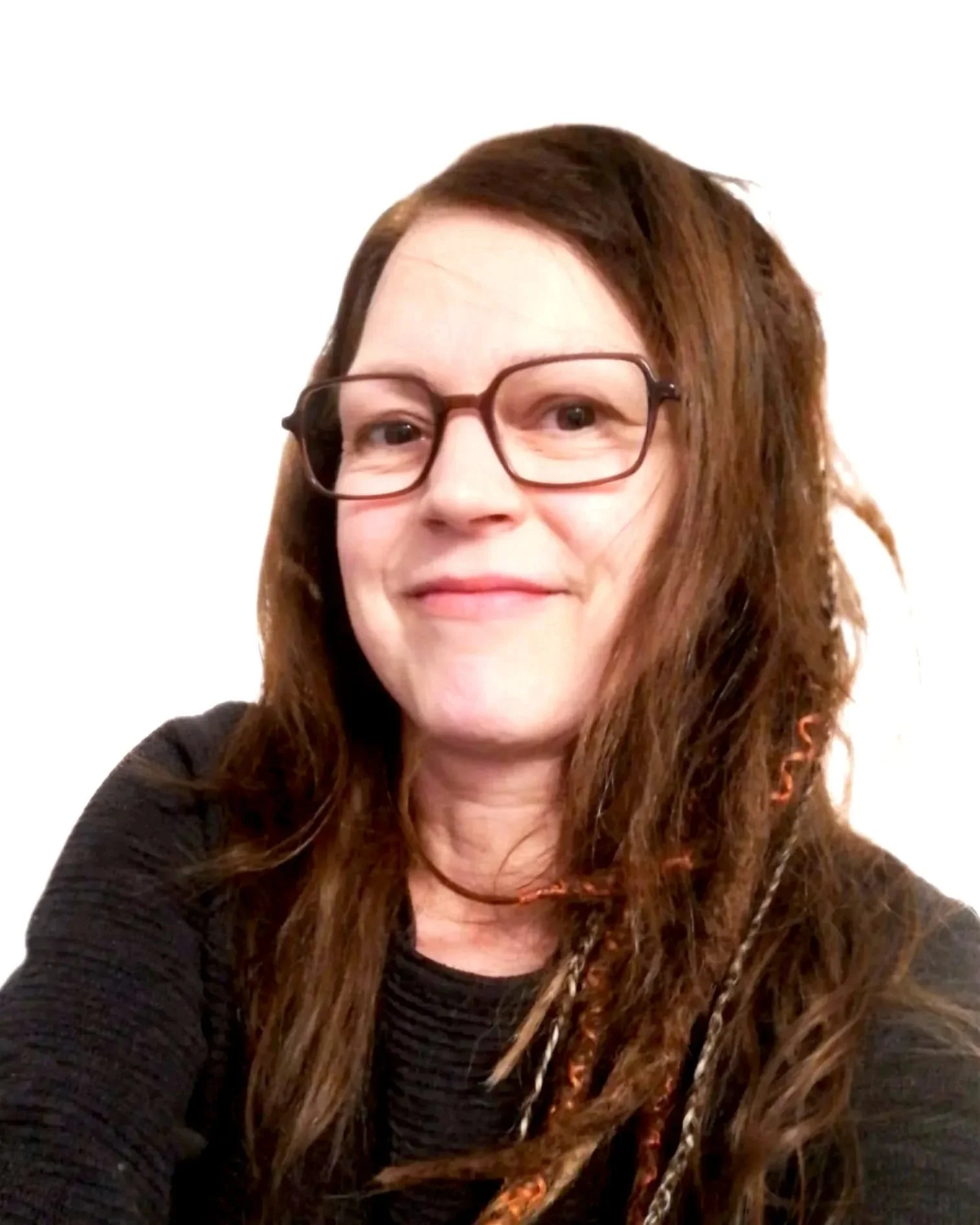 Nahaufnahme von Elvira mit langen, welligen, rotbraunen Haaren, eine Brille und ein schwarzes Oberteil und leicht lächelt, vor einem schlichten weißen Hintergrund.