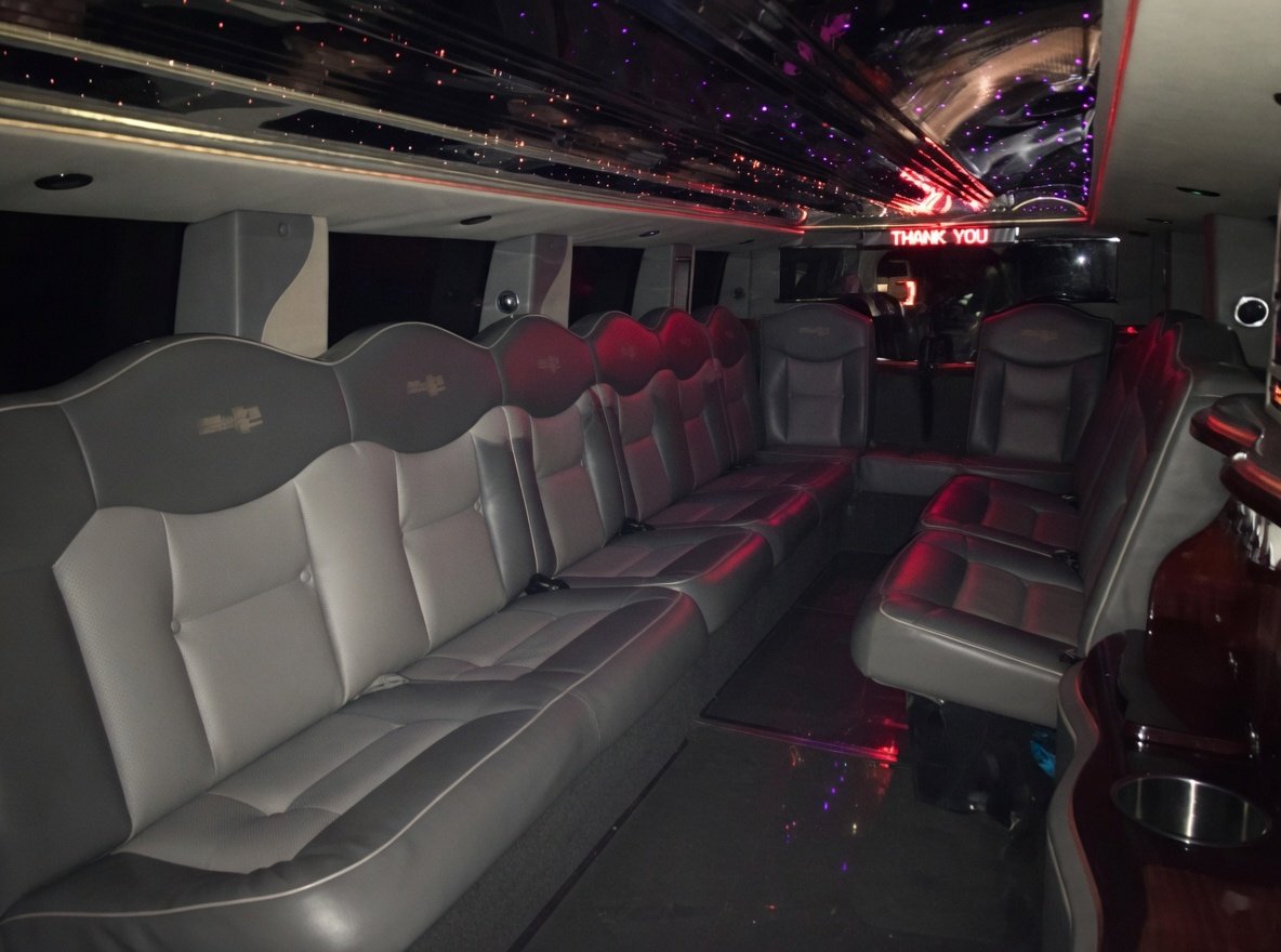 Interior of H2 Hummer limousine with gray leather seats, a starry sky ceiling, and a illuminated 'Thank You' sign in the front.