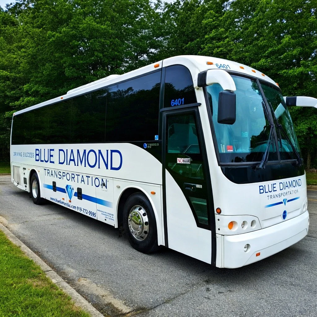 White Blue Diamond Transportation shuttle bus parked on a paved road with green trees in the background.