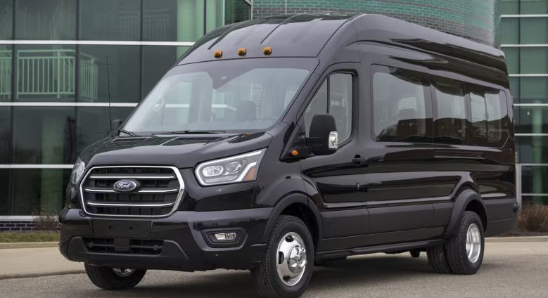 Black Ford Transit commercial van parked in front of a modern glass building.