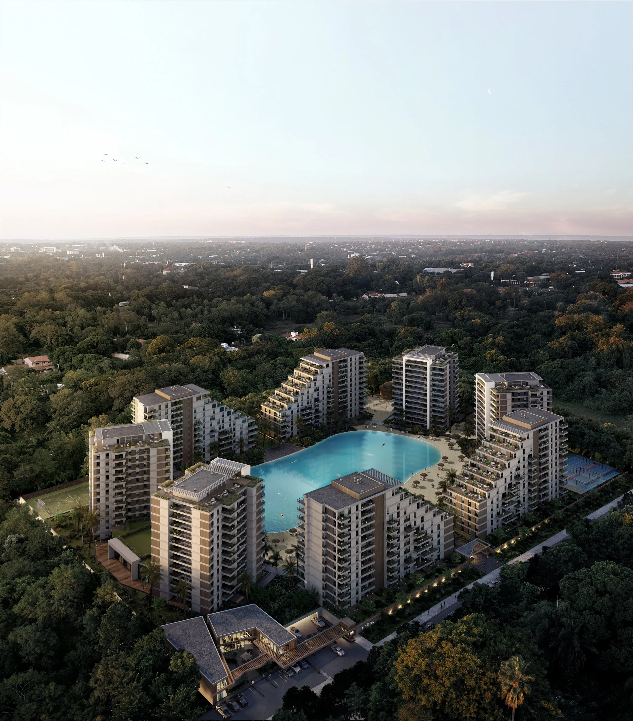 Aerial view of a modern residential complex with a large swimming pool at the center, surrounded by multiple high-rise buildings, green trees, and a distant cityscape under a clear sky.