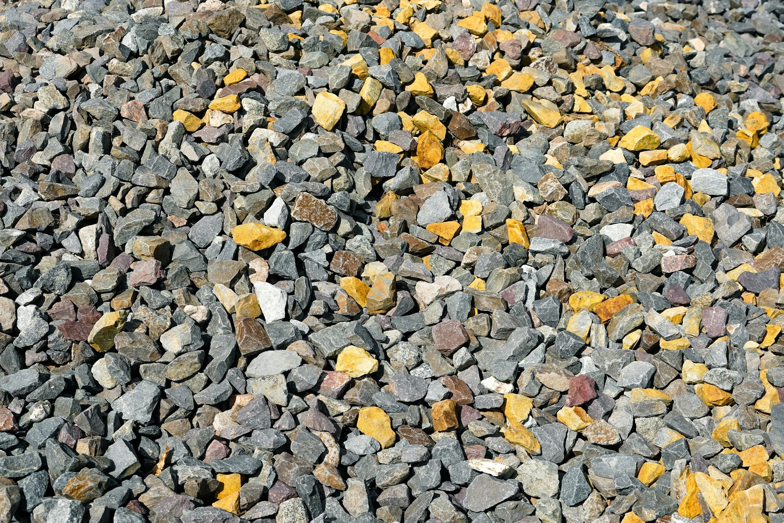 A close-up of a pile of small, jagged rocks and gravel, with colors including shades of gray, brown, and yellow.