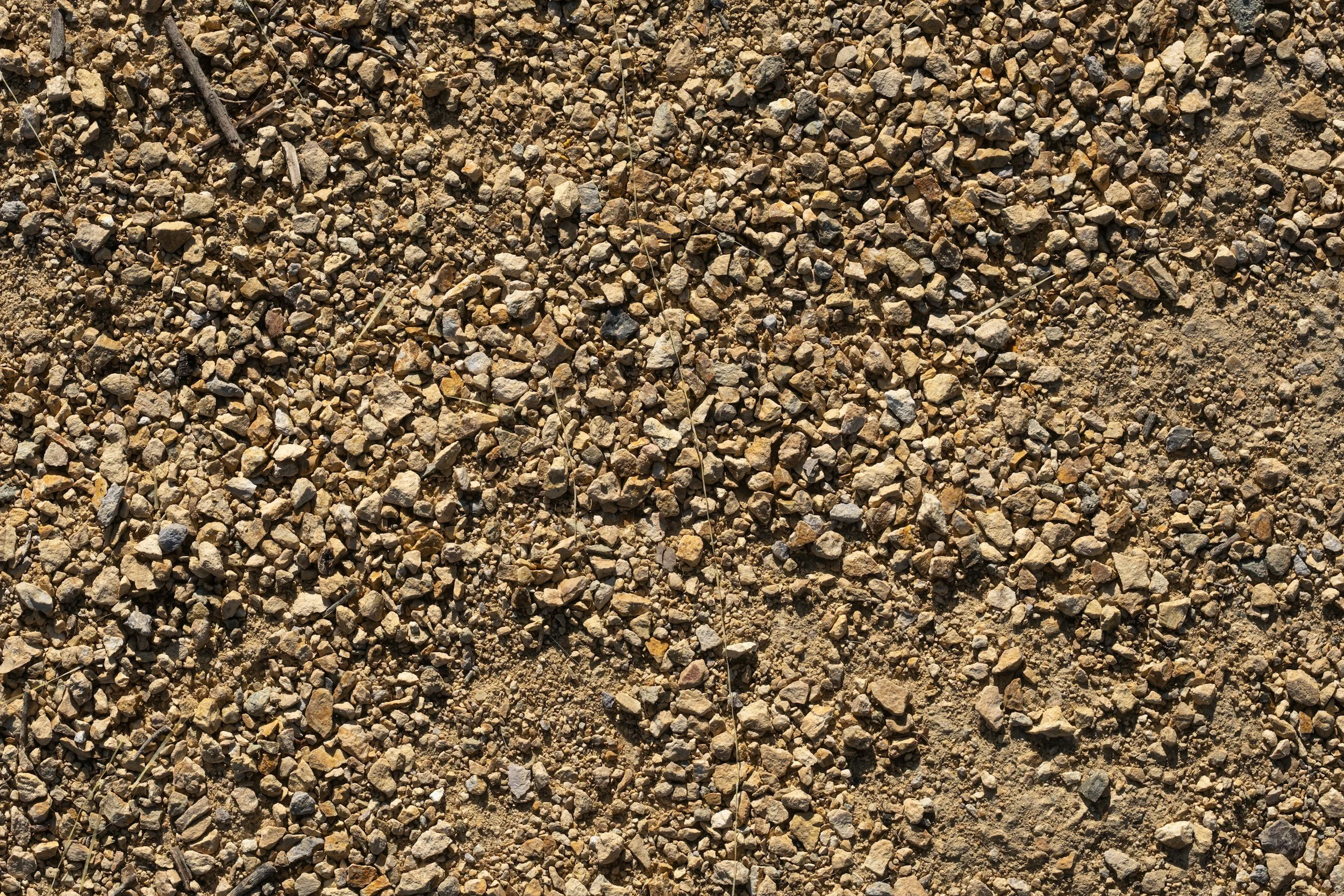 Close-up view of a surface covered with small rocks, pebbles, and dirt, typical of gravel or desert terrain.