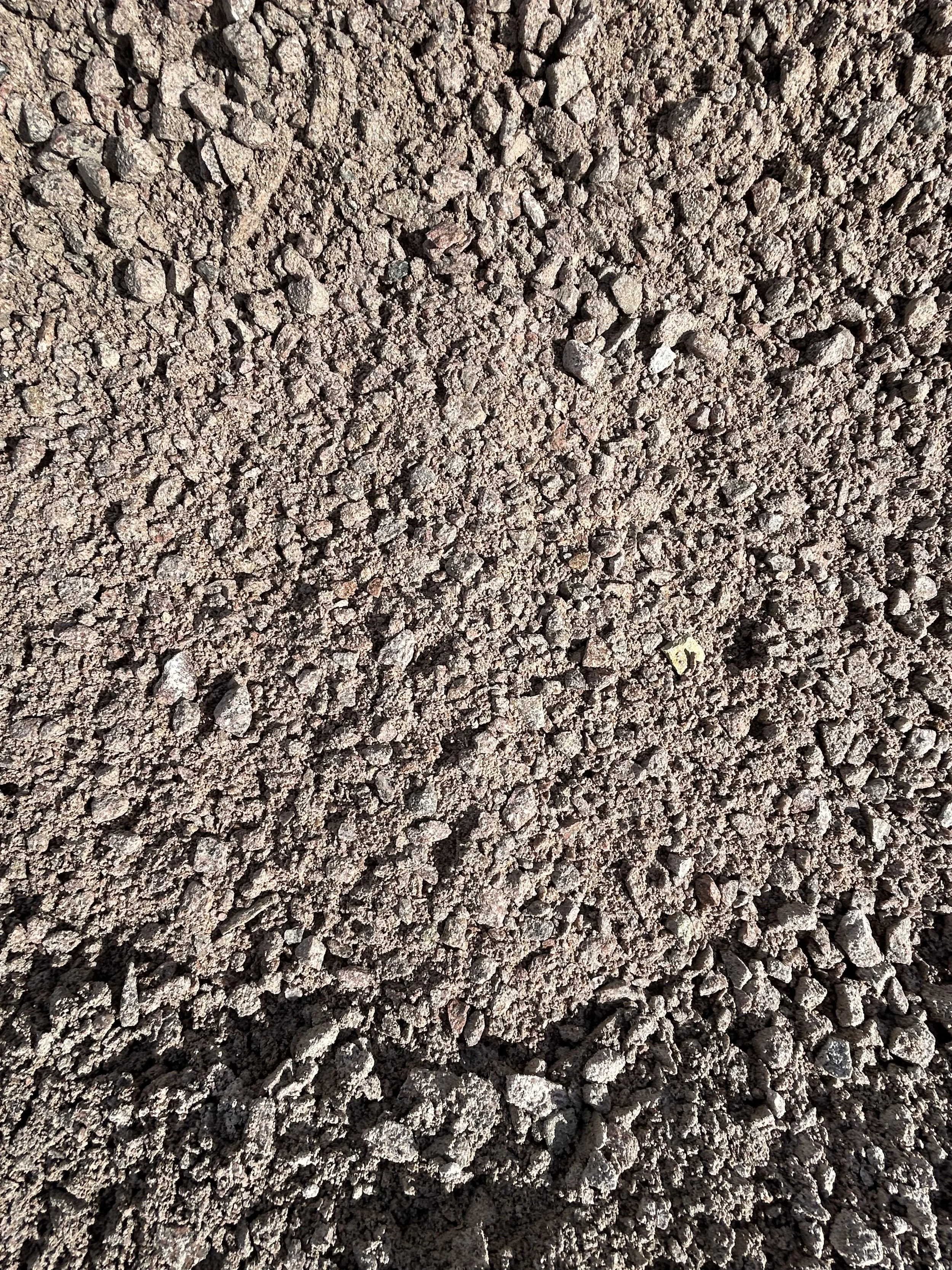 Close-up view of a dry stone wall made of irregularly shaped multicolored and textured stones stacked without mortar.