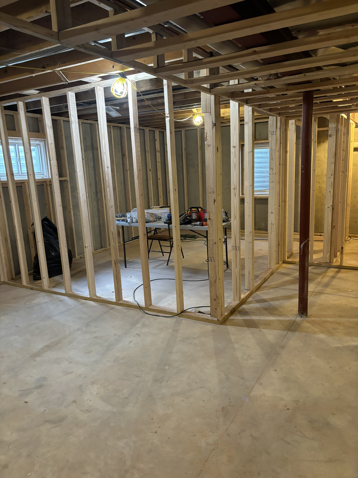 Interior view of a house under construction with exposed wooden framing, unfinished walls, and construction tools on a table.