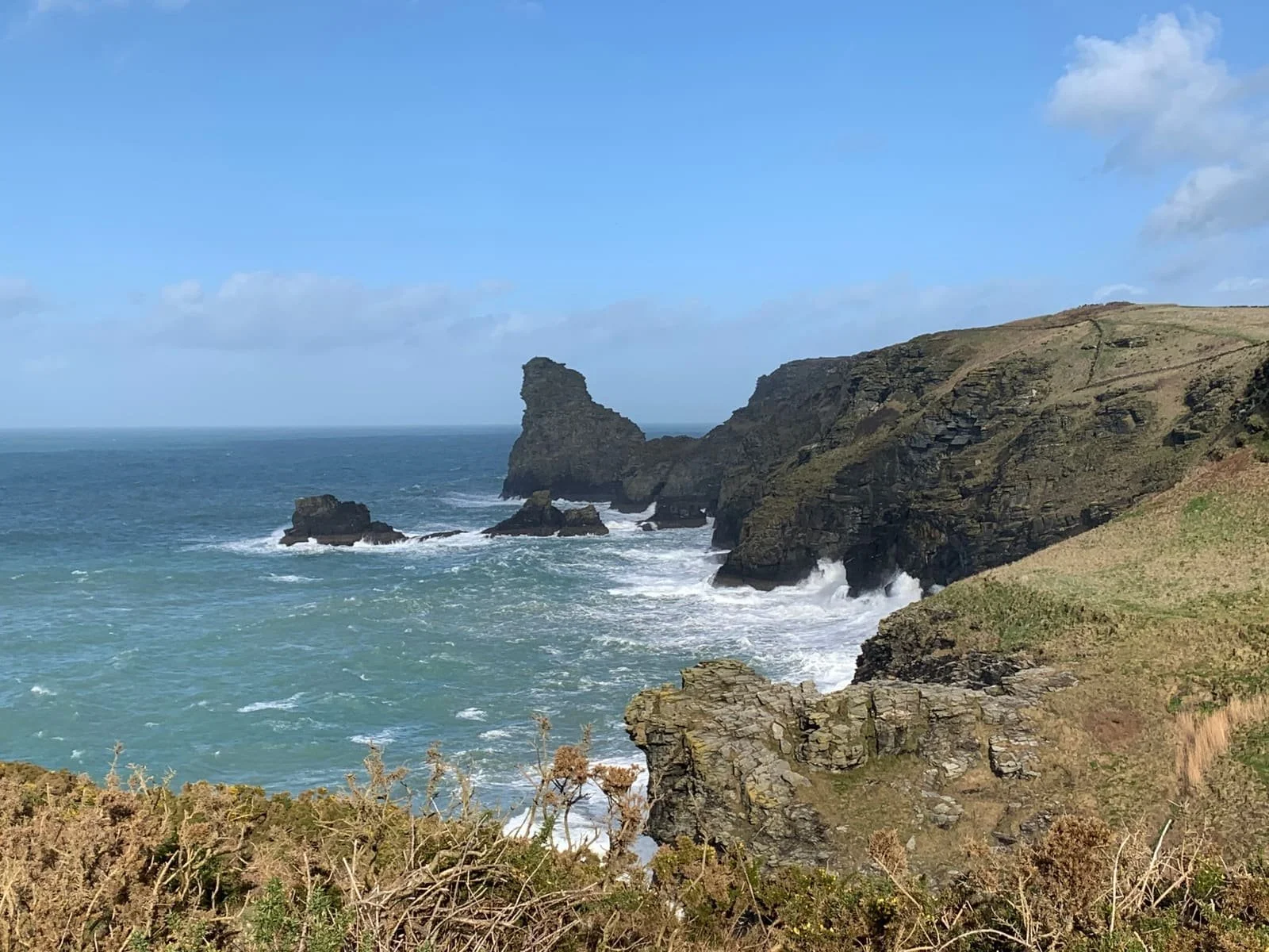 Cliffside overlooking the ocean with rocky formations and waves crashing against the rocks.