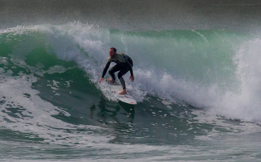 A man in a wetsuit surfing on a wave in the ocean.