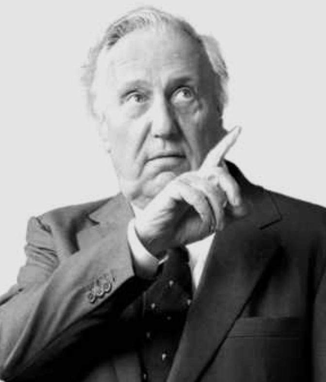 Black and white portrait of an elderly man in a suit, with a thoughtful expression and his finger touching his temple.