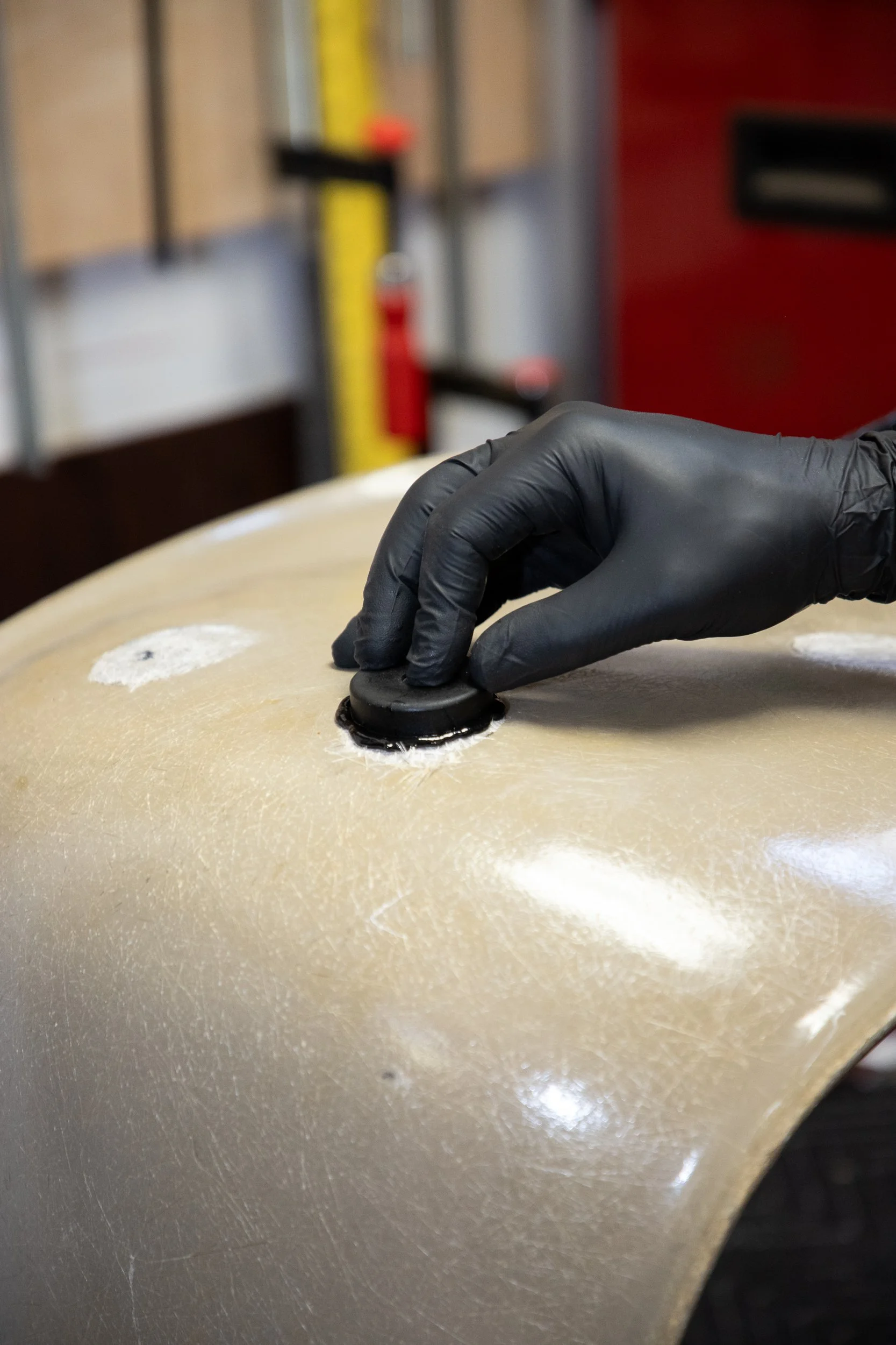 A hand wearing a black glove pressing a black button on a surface.