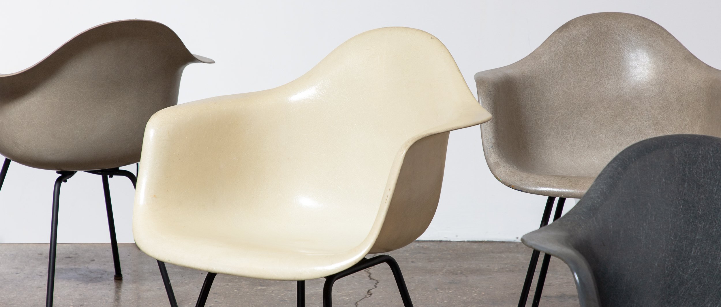 Multiple modern chairs in neutral colors arranged against a plain background.