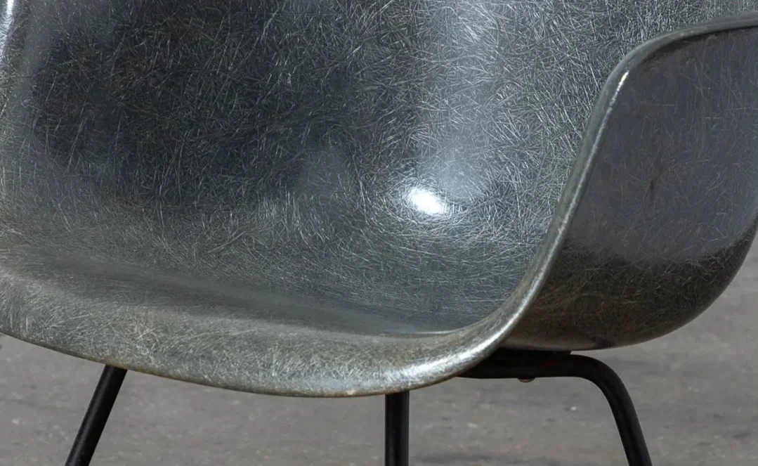 Close-up of a worn, black plastic or metal chair with metal legs, set on a concrete surface.