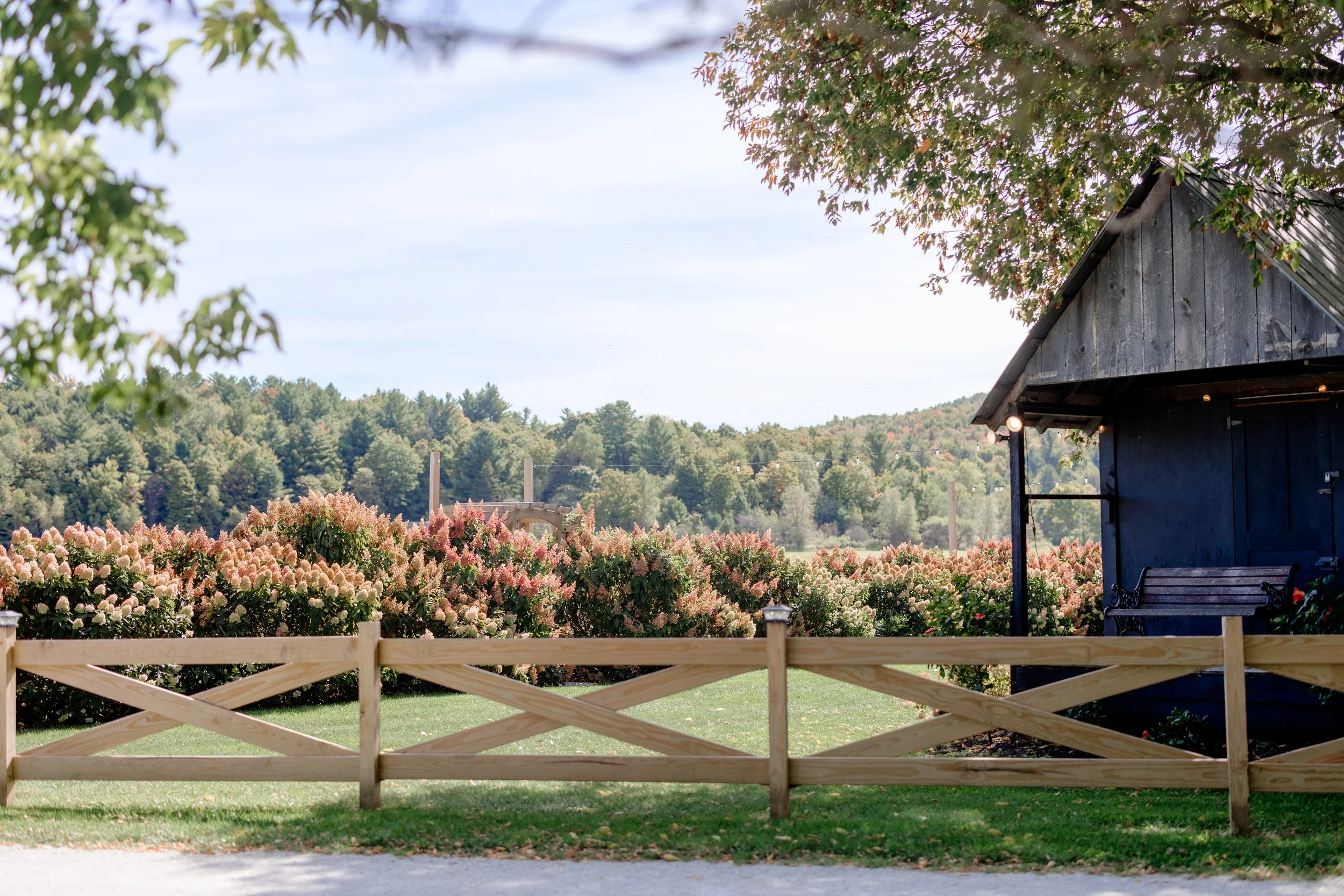 Rustic white outbuilding and wooden fence at Swiss & Bloom Farm, a quiet backdrop for wedding portraits and guest arrival moments.