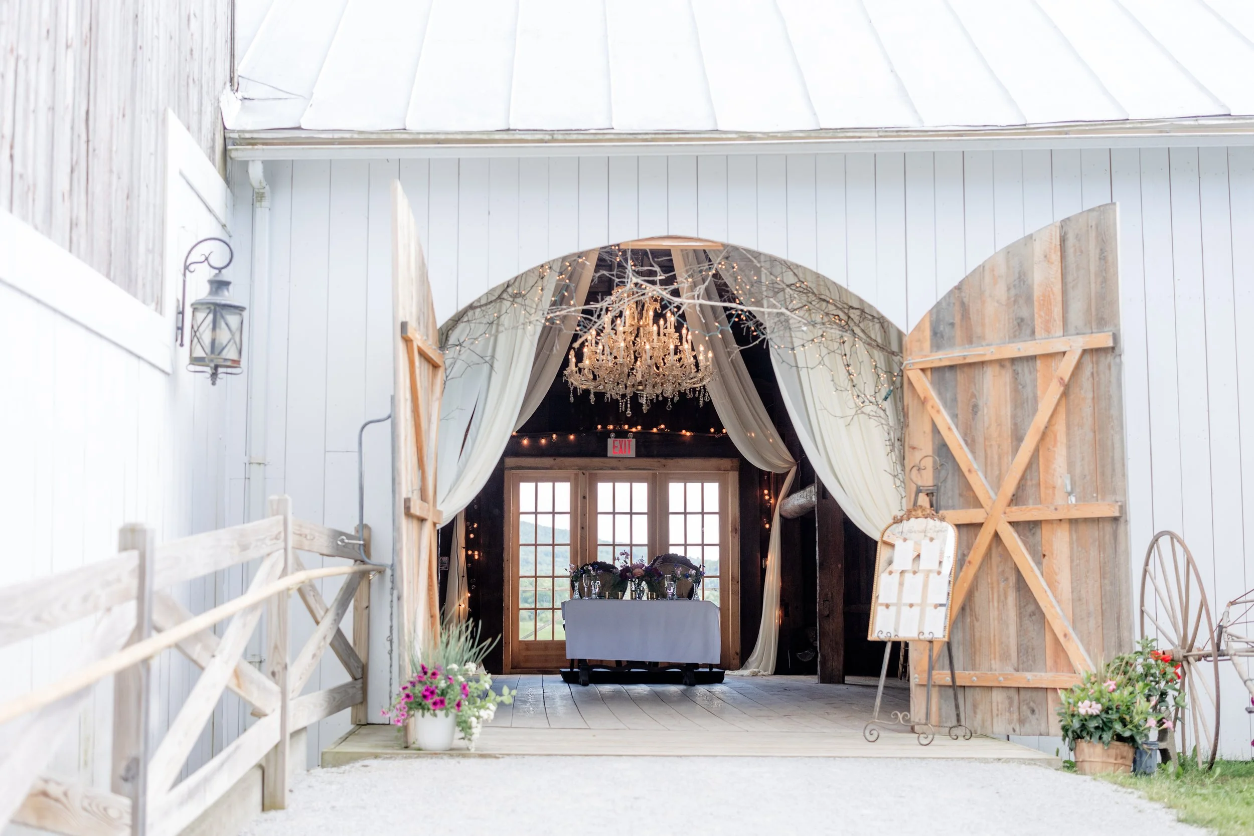 Wide view of the Wedding Barn with open doors and landscaped florals at Swiss & Bloom Farm.