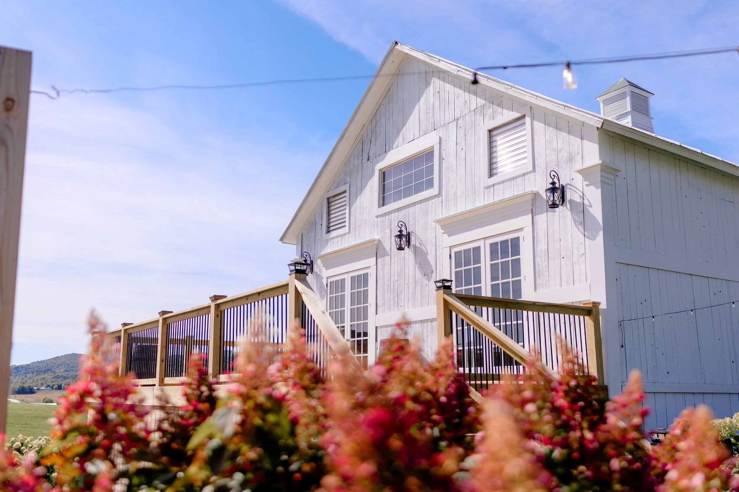 Back view of the Wedding Barn at Swiss & Bloom Farm, framed by blooming flower gardens in the Vermont countryside.