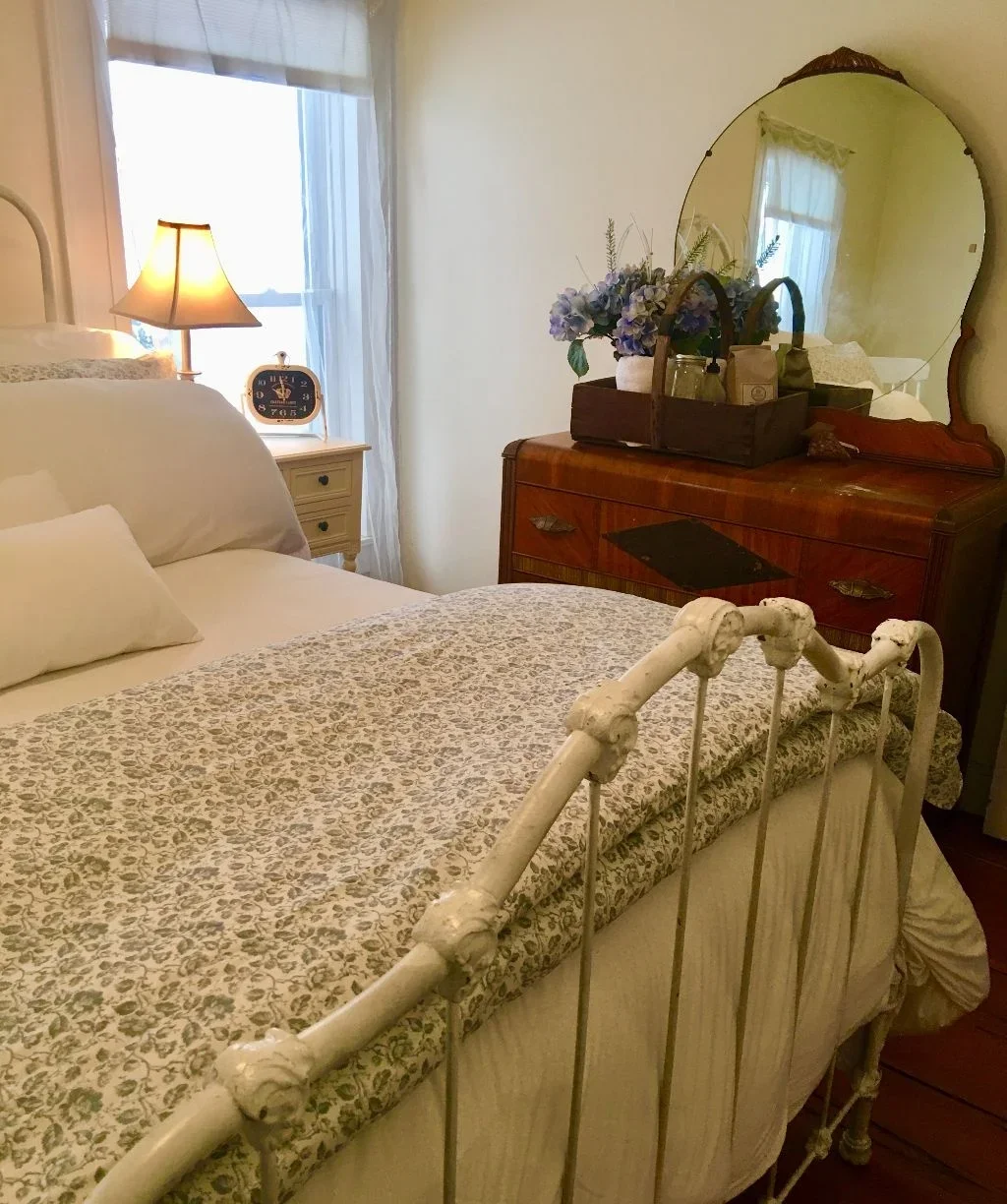 Bedroom inside the Farmhouse at Swiss & Bloom Farm with floral bedding, wooden furniture, and warm lighting.