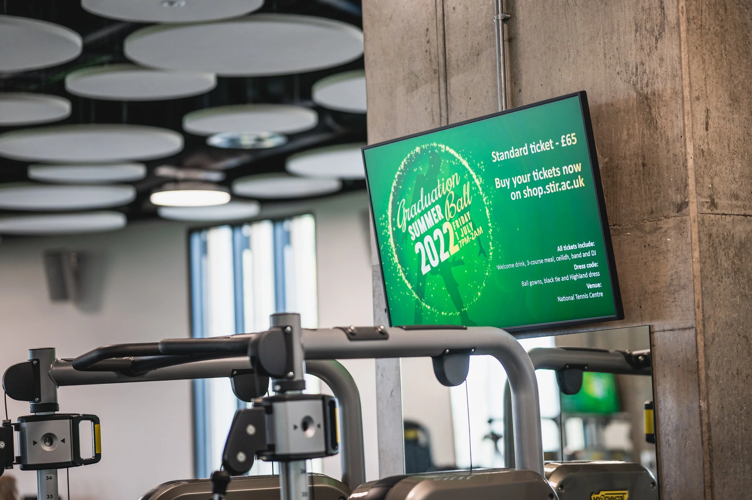 Digital screen advertising graduation summer ball event at a sports or conference venue.