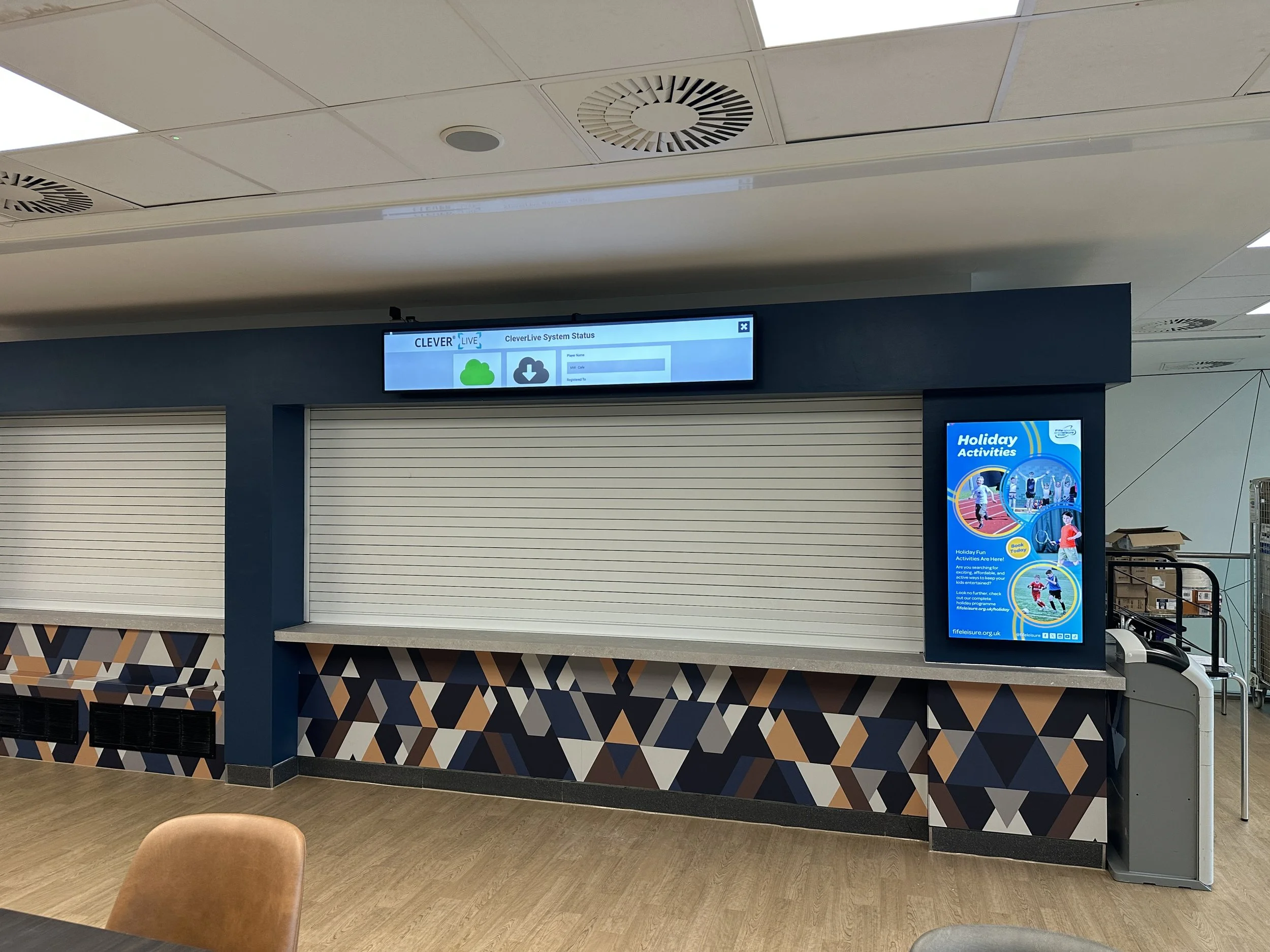 A specialised screen placed to fill a long and narrow strip above a closed shutter in a restaurant