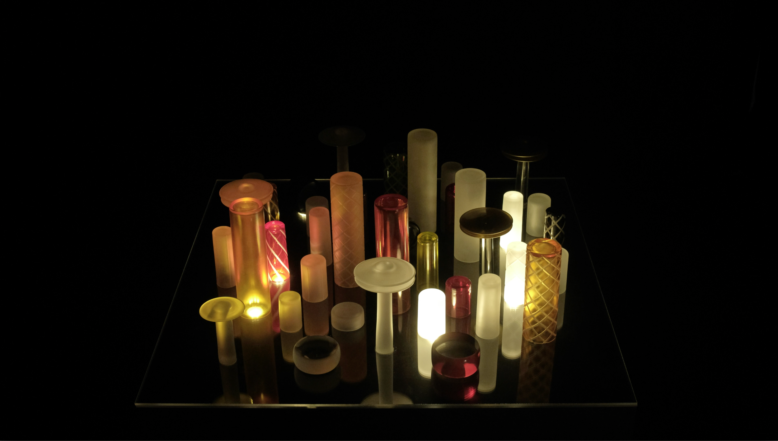 Dit ljuset leder - Färglada glasskulpturer - i ett mörkt rum.png