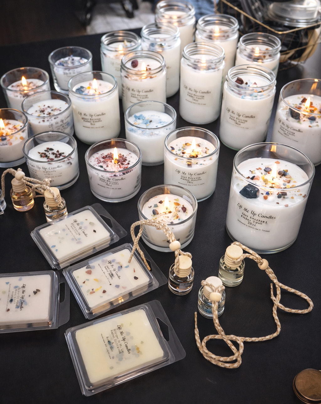 Collection of handmade scented candles in glass jars with decorative stones, arranged on a table.