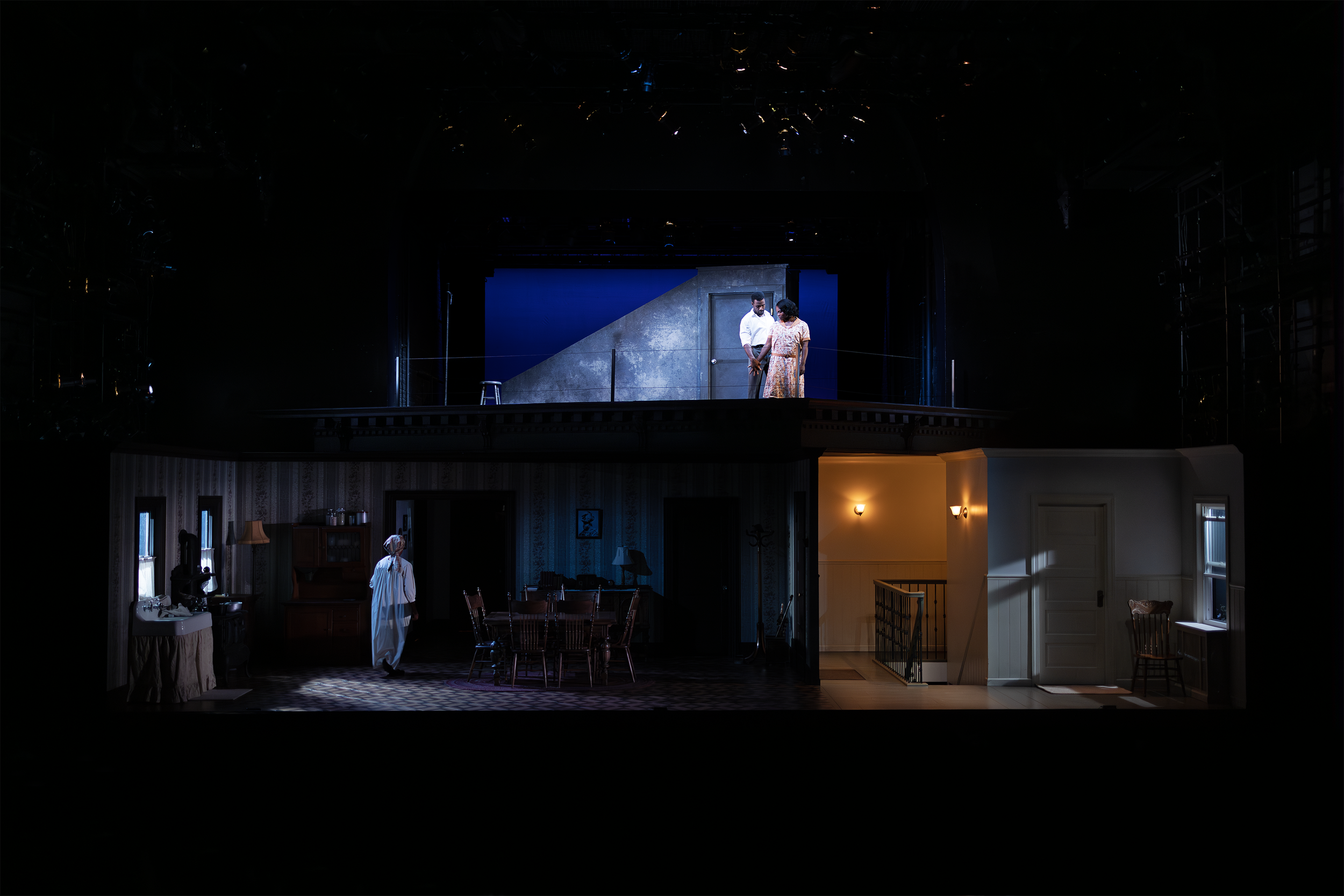 Theatrical stage set with multiple rooms and actors